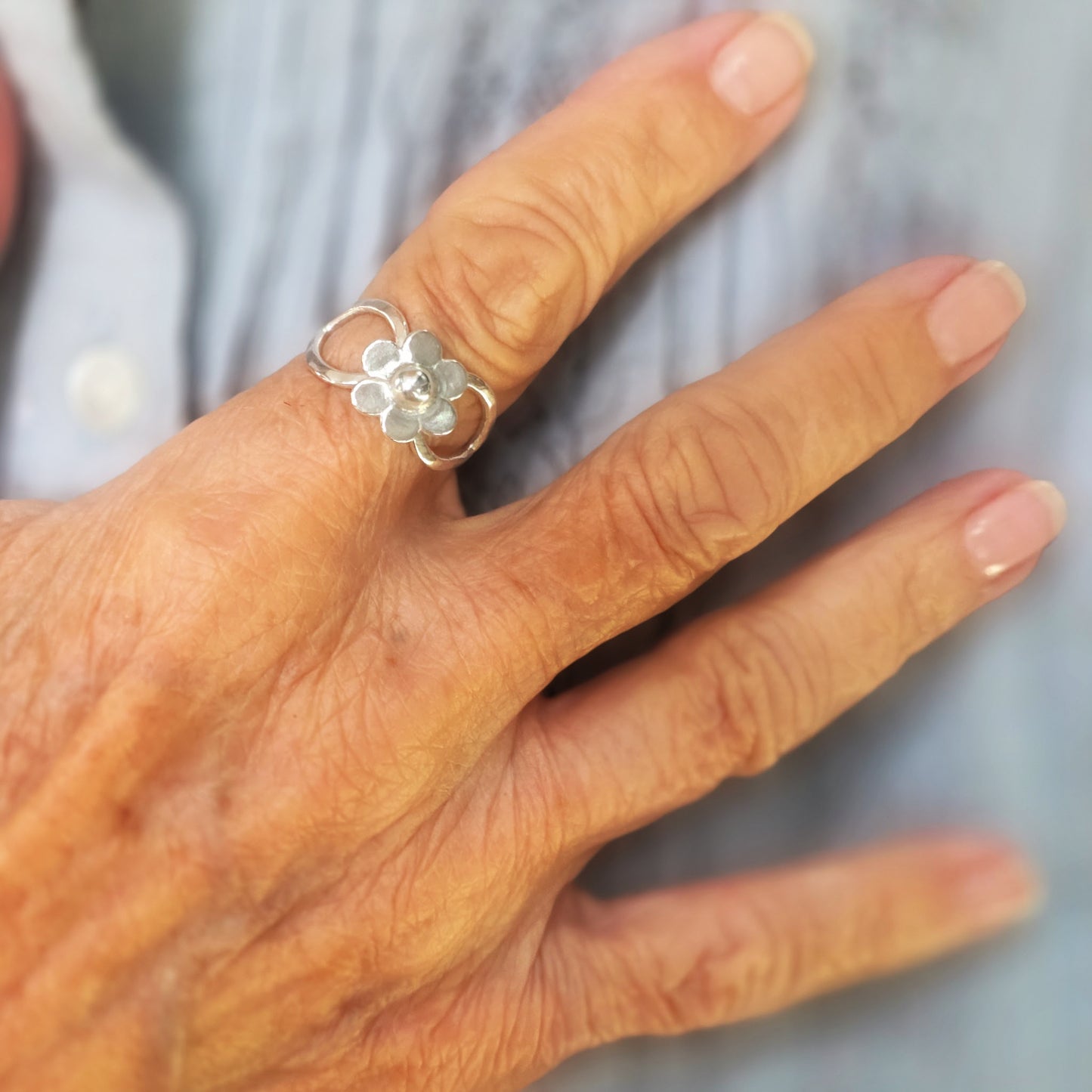 Handmade daisy flower ring in Argentium silver, worn on hand, artisan jewelry