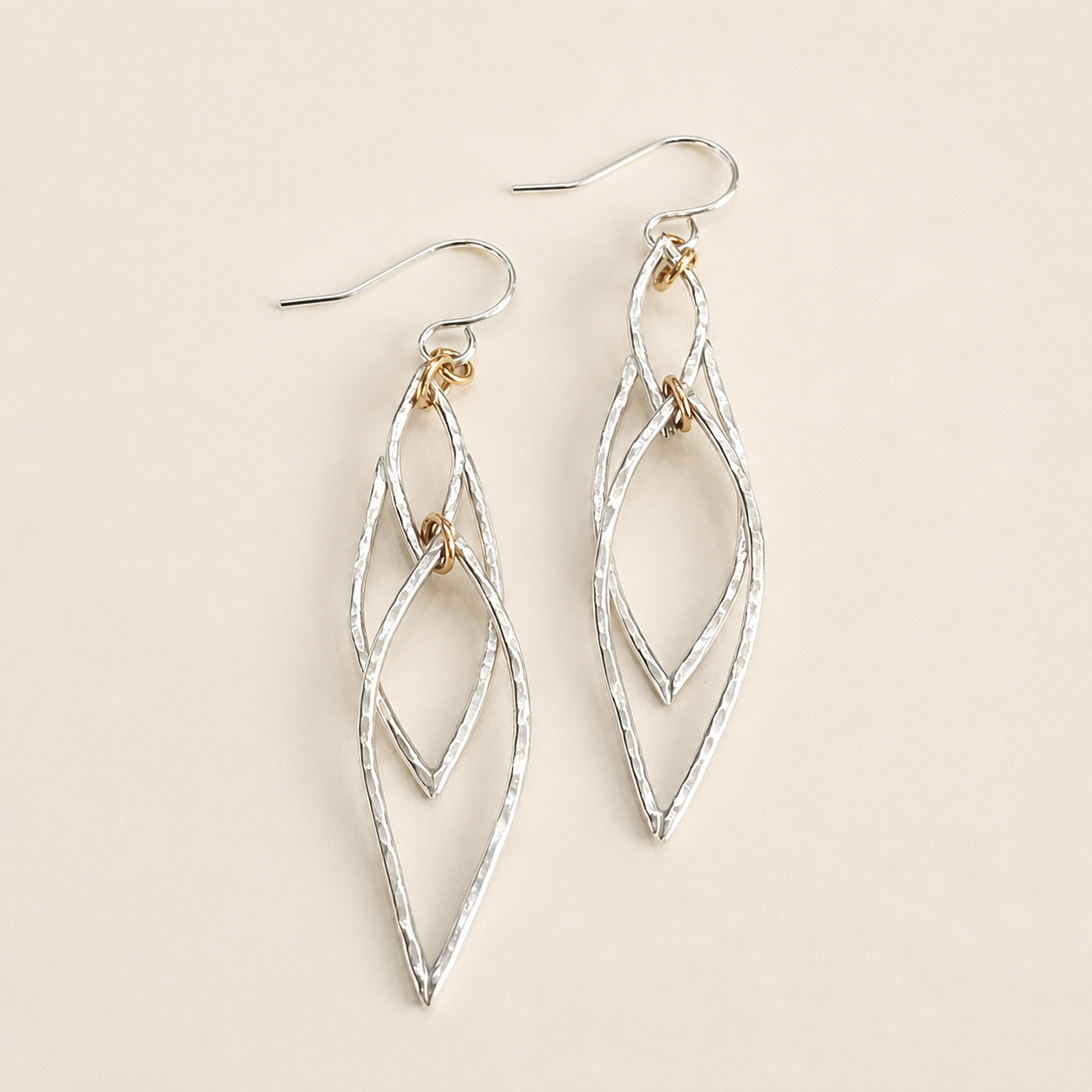 Limited-edition River Dragon Earrings in hammered Argentium silver with gold-filled rings on a cream background