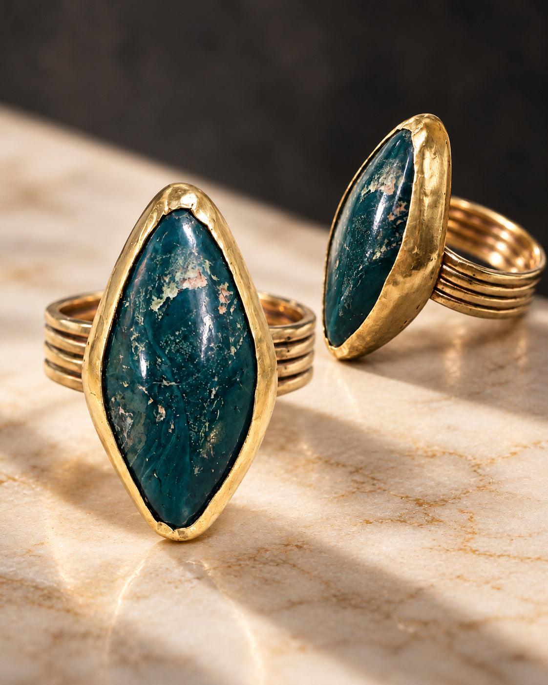 Two editorial views of The Mariposa Ring by Lepa Jewelry, highlighting the green mariposite stone, warm sculptural brass setting, and substantial four-strand band.