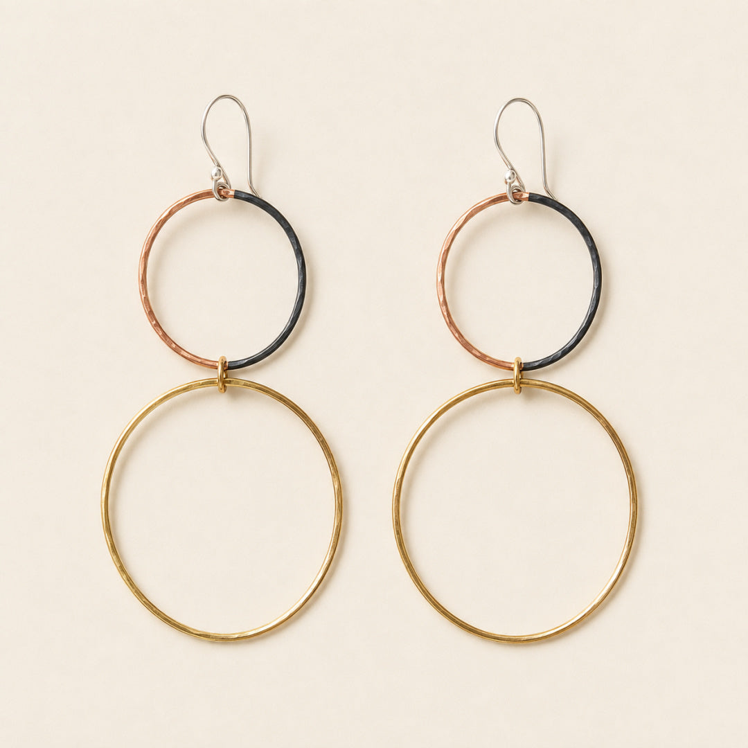 Pair of Meridian Hoops with brass lower hoops, partially oxidized copper upper hoops, and Argentium silver earwires on an ivory background