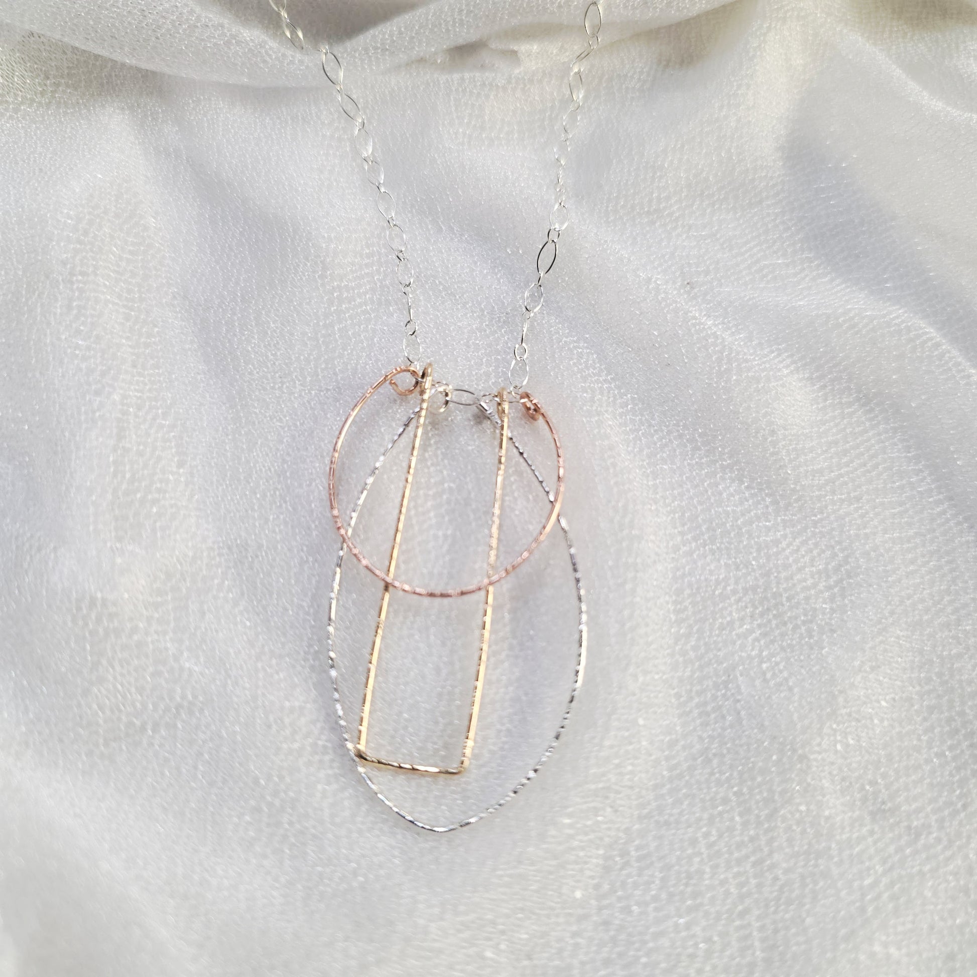 . Tri-color Art Deco Necklace with layered geometric pendants on sterling silver chain.