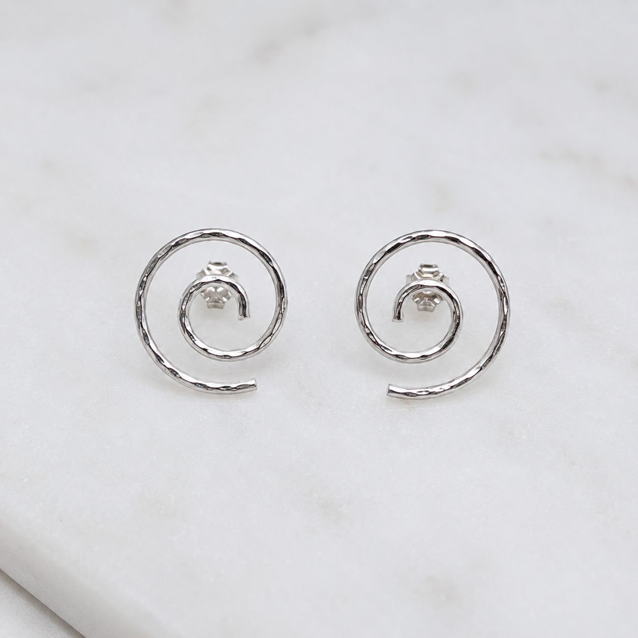 Argentium silver spiral stud earrings on marble surface, modern minimalist jewelry
