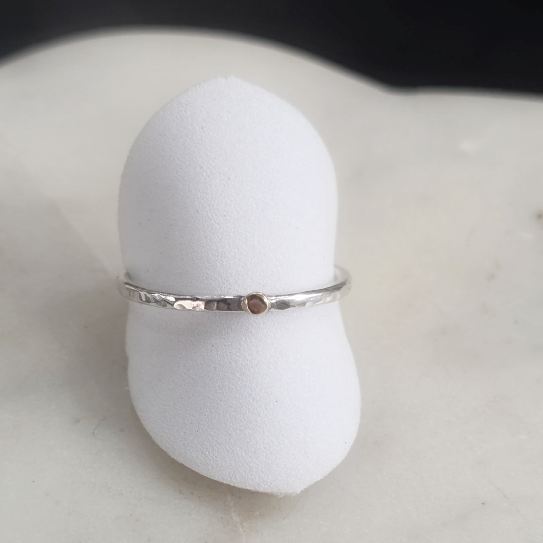 The Golden Moment Ring displayed on a white ring stand, highlighting the hand-hammered Argentium silver band and solid 14k gold accent.