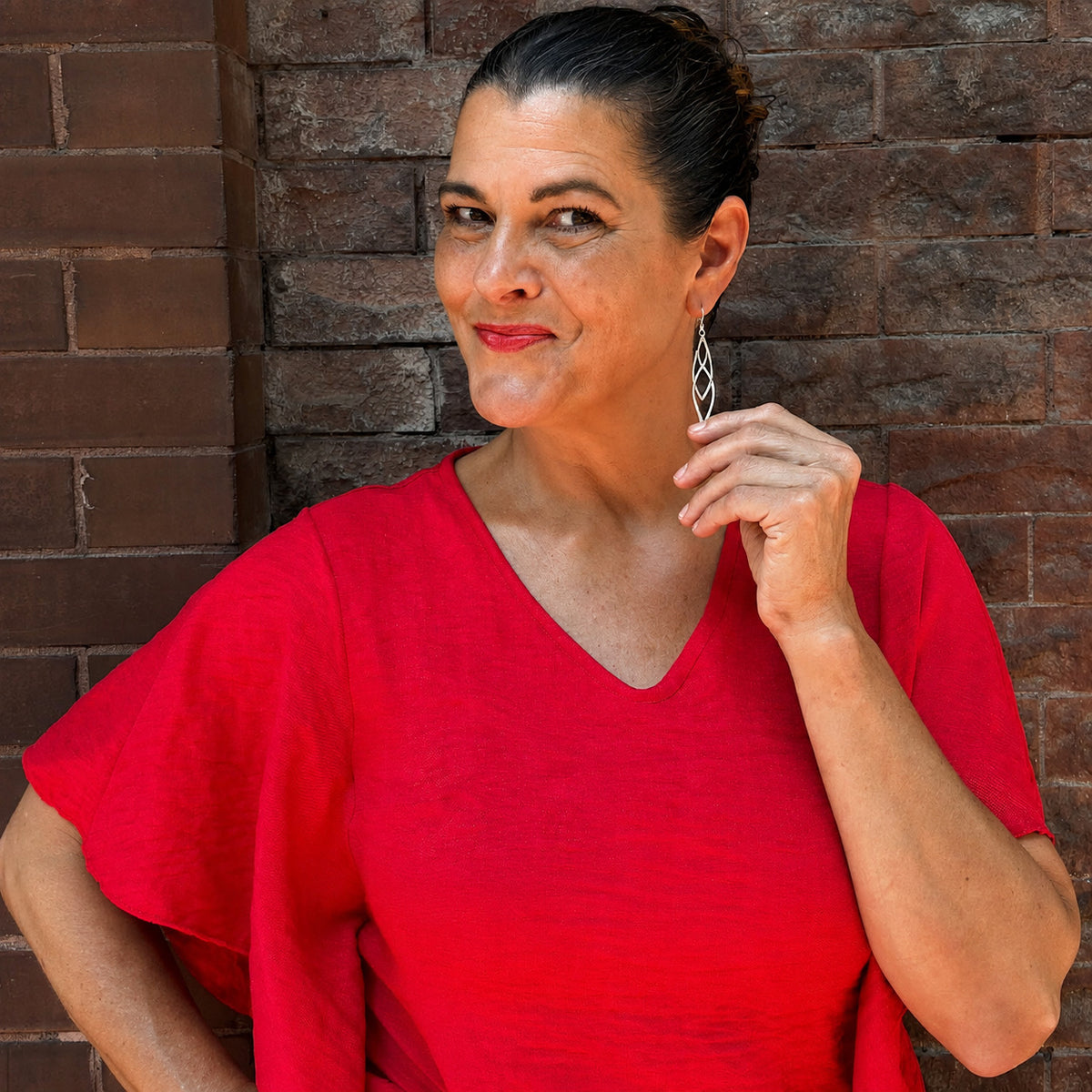Kimberly Story models the long sculptural River Dragon Earrings in Argentium silver and 14k gold-filled rings while wearing a red dress in Paducah, Kentucky.
