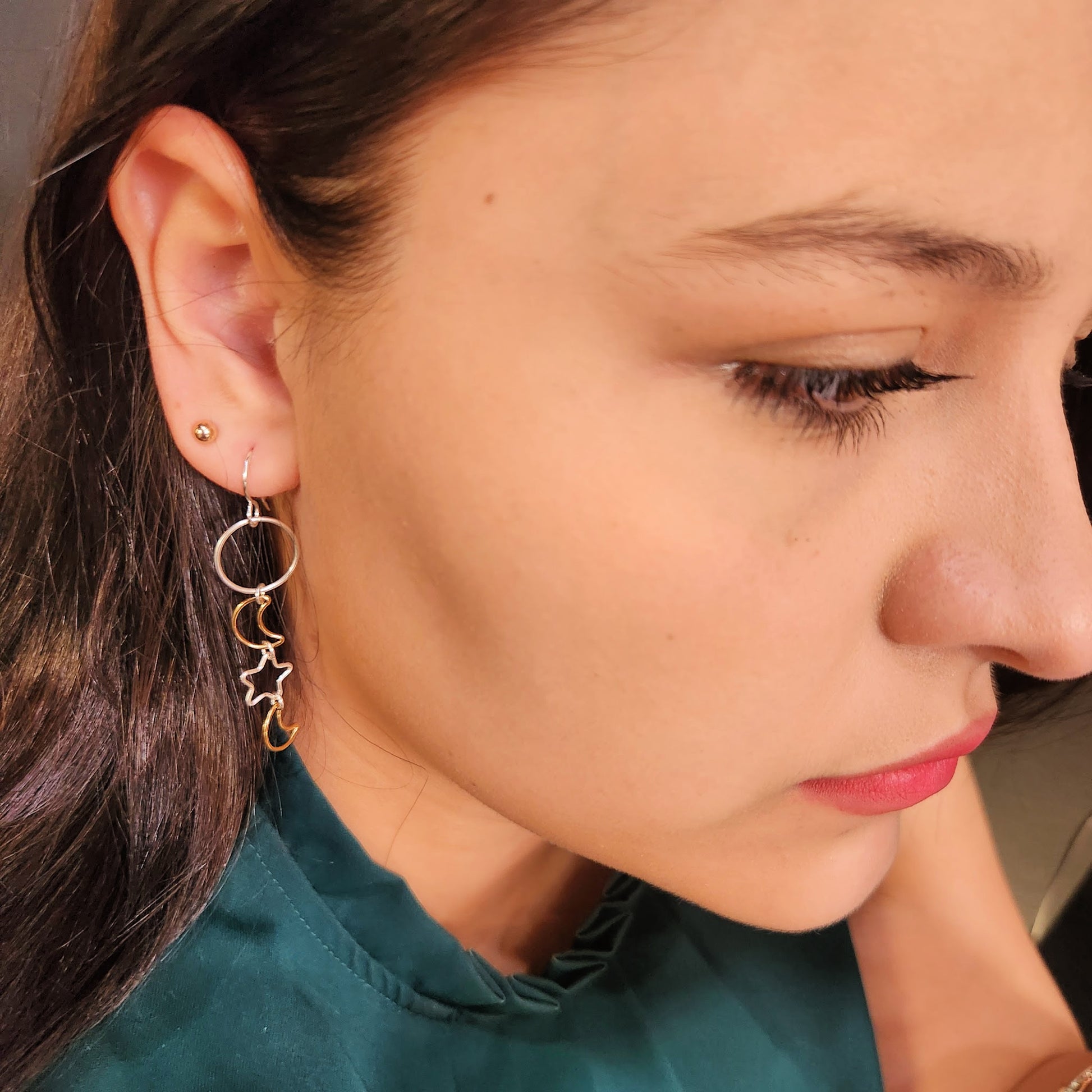 Woman wearing mixed metal dangle earrings with silver stars and gold moon charms
