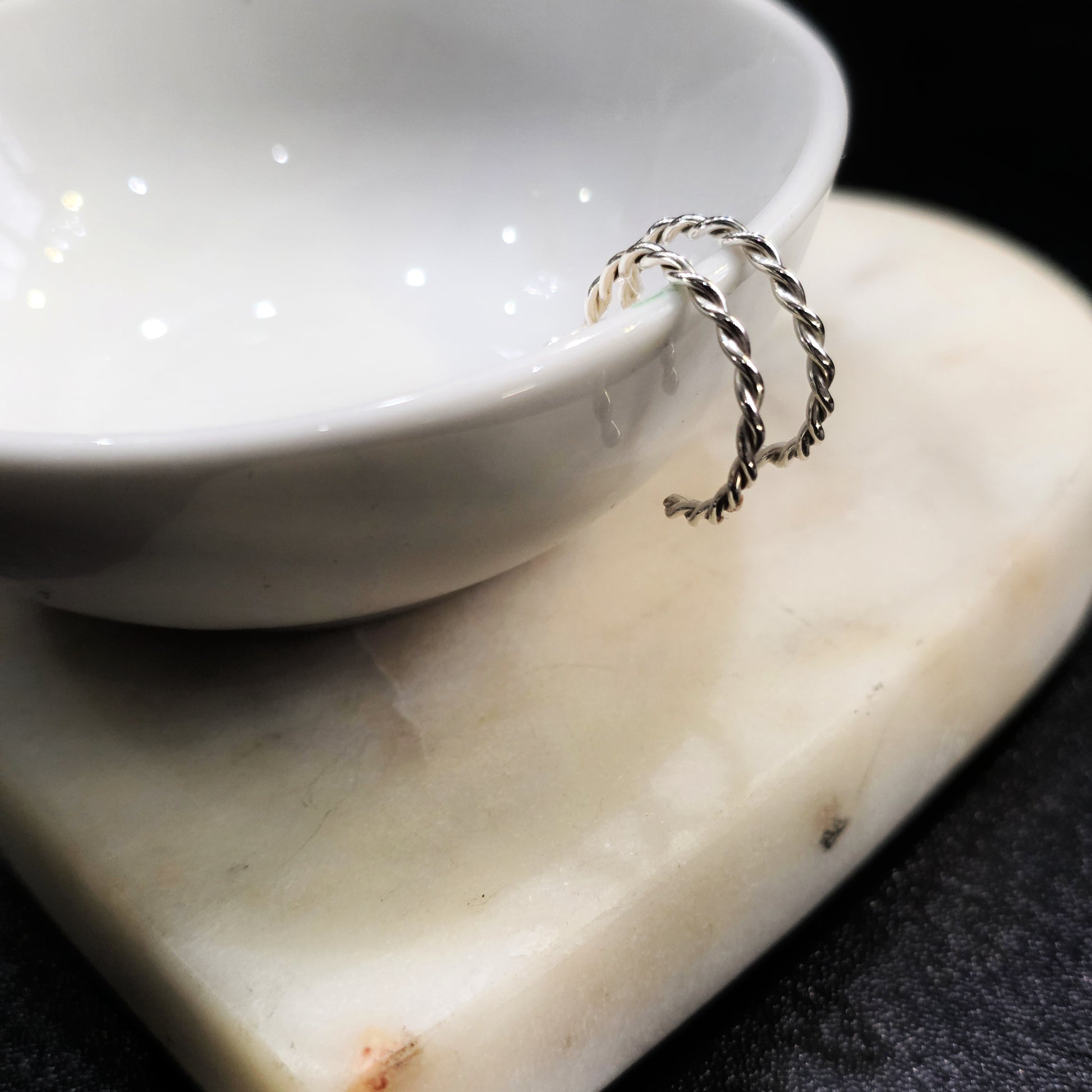Close-up of handcrafted Argentium silver twisted half hoop earrings with radiant shine.