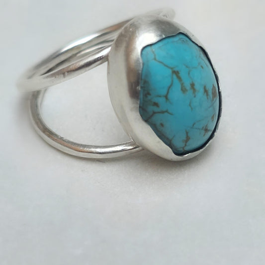 Centered flatlay of turquoise dome ring on white background.