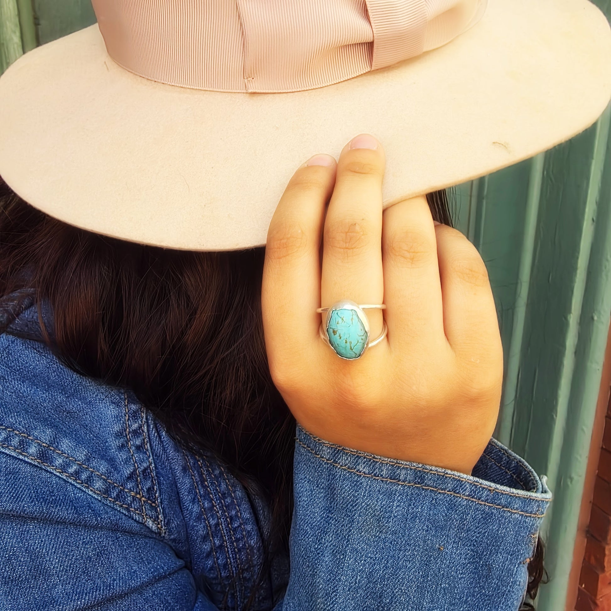 Woman wearing Voice of the Sky Turquoise Ring with a wide-brim hat.