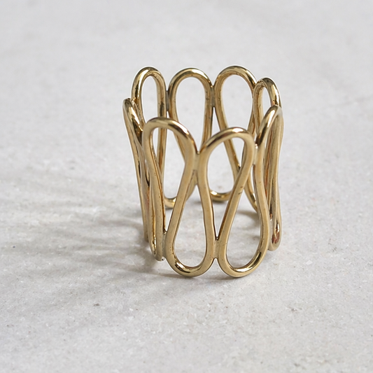 Aegis Ring by Lepa Jewelry, sculptural gold statement ring with flowing curved design on neutral stone surface