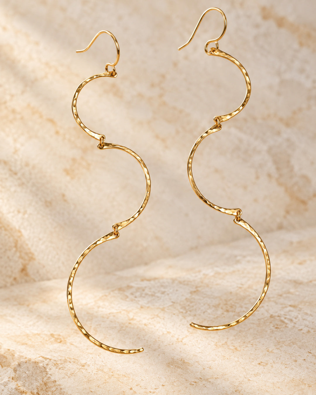 Suspended Cadence Earrings featuring three graduated, hand-hammered gold-filled arcs against warm ivory stone.