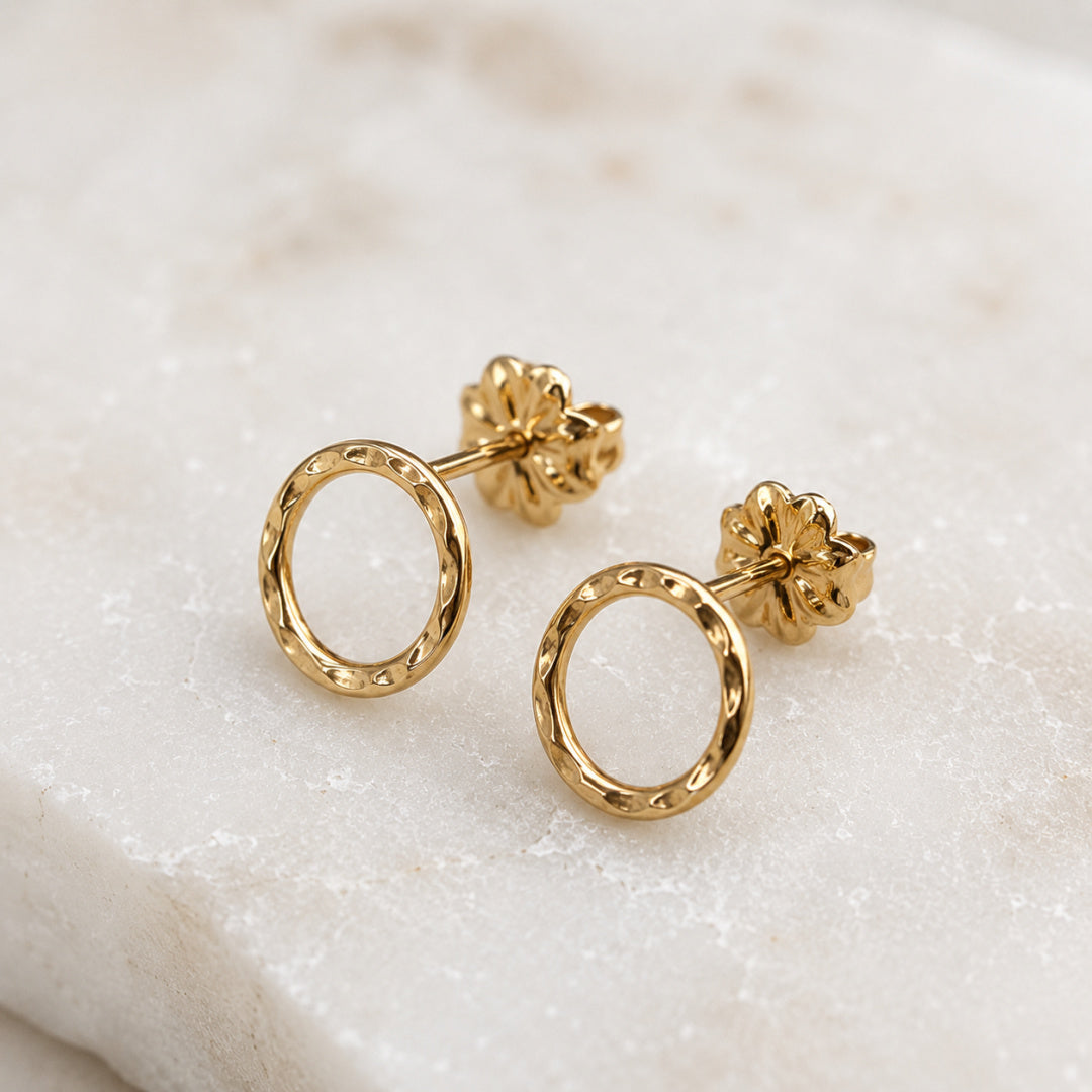 Side view of gold-filled Karma Stud earrings showing post and hammered circular form on neutral background