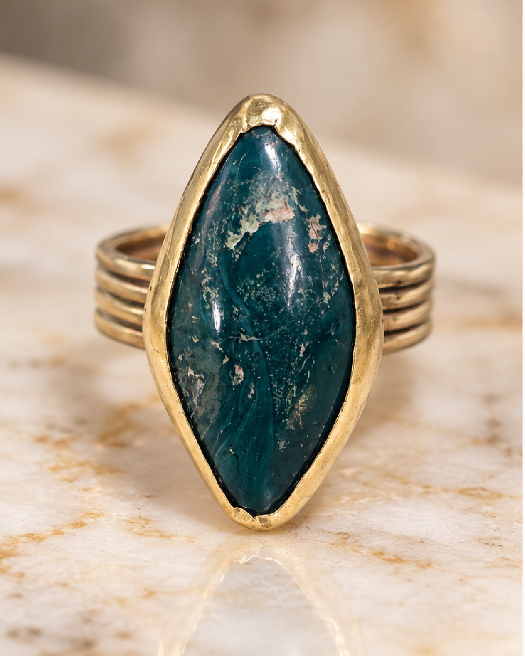 The Mariposa Ring by Lepa Jewelry, featuring an elongated deep green mariposite stone with natural pale markings, framed in a sculptural brass bezel.