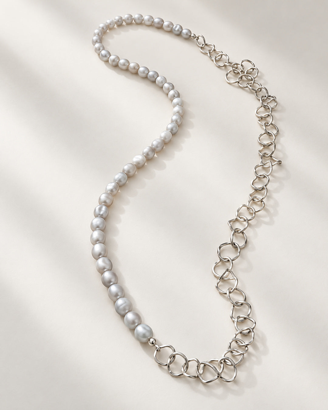Full view of the Selene Necklace showing its asymmetrical design with pale grey freshwater pearls and individually formed Argentium silver links.