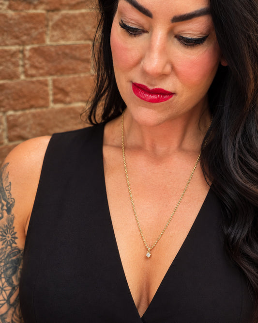Woman wearing the Lepa Jewelry Sultry Drop Necklace, featuring a delicate CZ pendant on a 24-inch gold-filled chain with a plunging black neckline.