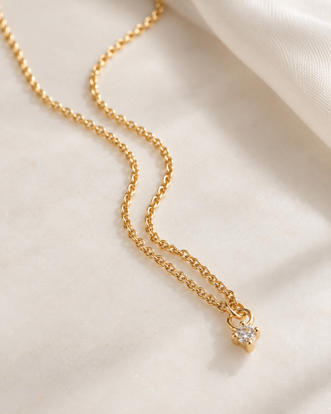 Delicate 24-inch gold-filled rolo chain with a single CZ drop pendant, styled against a soft white background.