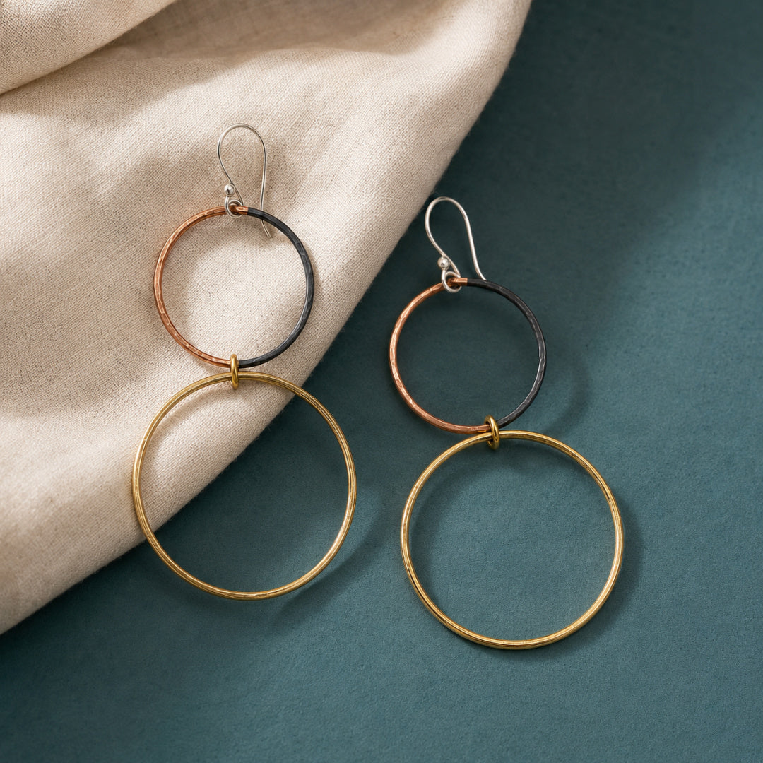 Pair of Meridian mixed metal hoops arranged on deep teal with cream linen