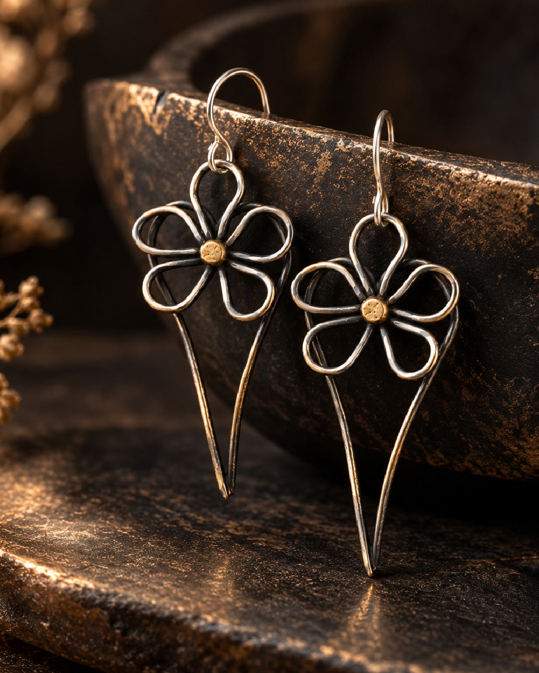 Wild Rose Heart Earrings displayed against a dark bronze background, highlighting oxidized heart frames, sculptural silver flower petals, and contrasting gold centers.
